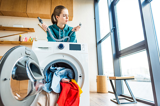 Confused woman next to broken laundry appliance