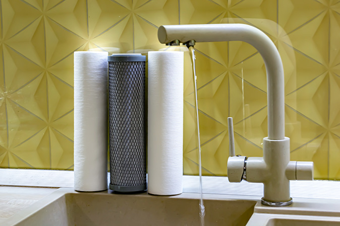 A faucet water filter being used to fill a cup.