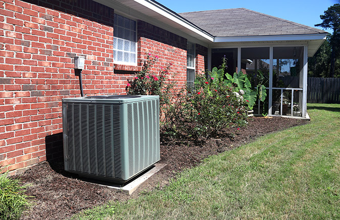 An air conditioner outside of a brick house.