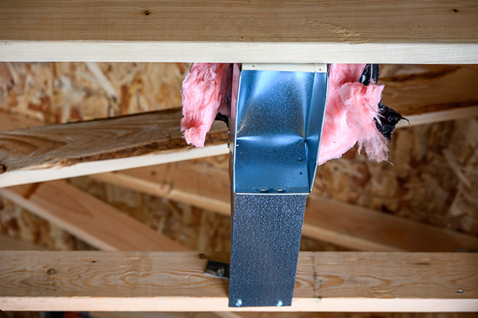 An air vent in a home connected to flexible ductwork being installed.