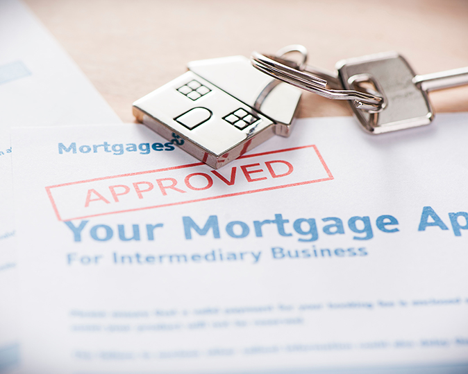 A house key rests on top of an approved mortgage application.