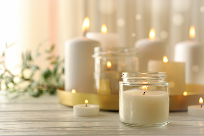 An arrangement of lighted, scented candles displays on a wooden table.