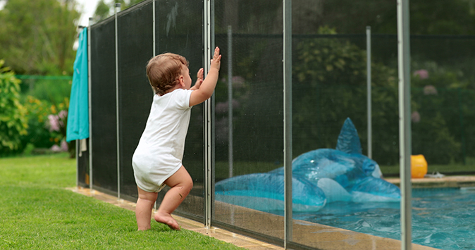 Toddler leaning on pool safety fence