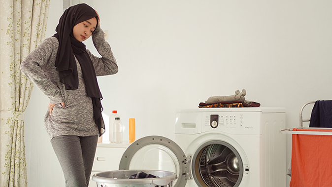 A young woman scratches her head trying to deal with a broken dryer which might not be covered by a home warranty.