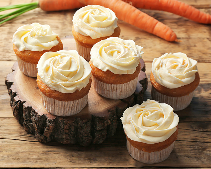 arrot cake cupcakes on a wooden display.