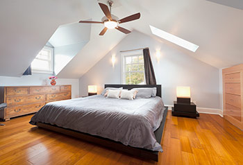 A bedroom with the ceiling fan light on 