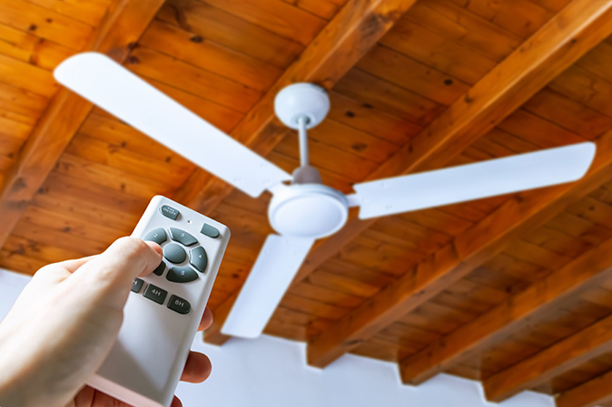 Person using a remote to control a ceiling fan 