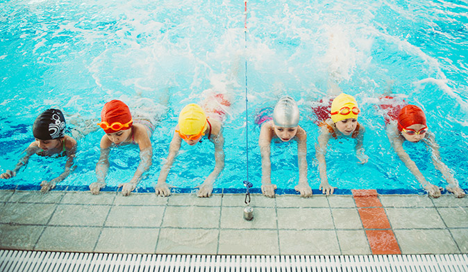 A group of kids taking swimming lessons.