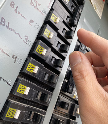 A person’s hand reaching for a circuit breaker switch