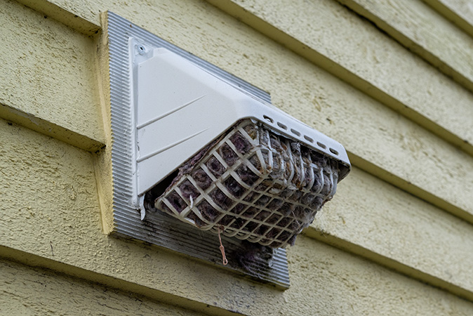 An exterior dryer vent that is clogged with lint and debris.