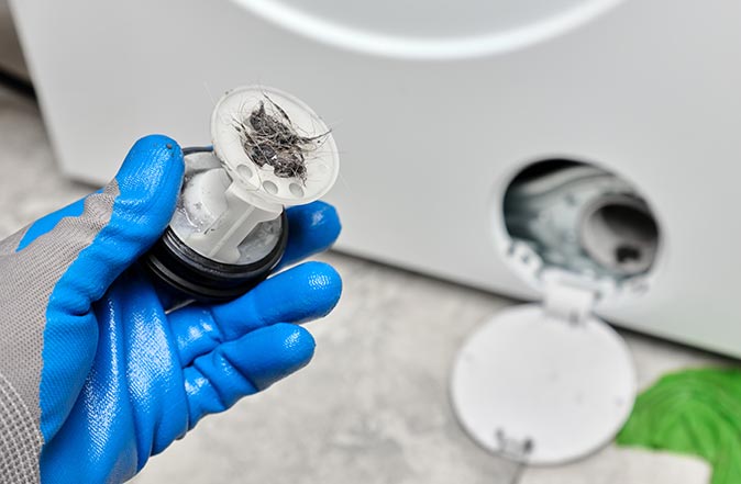 Closeup of a dirty washing machine drain filter in front-loading washer