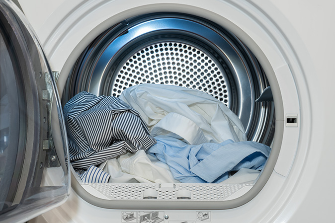 A clothes dryer machine with washed and dried shirts.