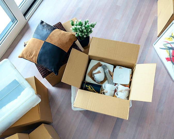 A living room in the process of being decluttered, with several full cardboard boxes.
