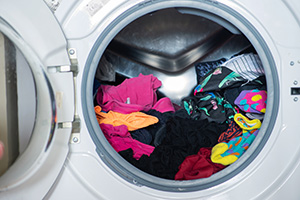 Front-loading washing machine full of colorful clothes with door open