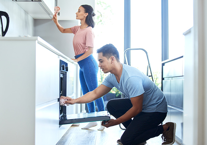 Young couple cleaning an oven and kitchen