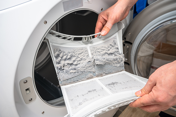 A person holding a dirty dryer lint trap.