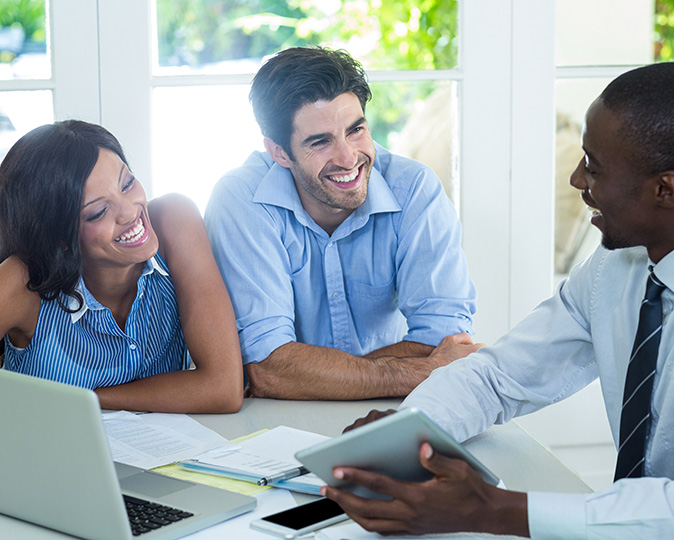 A real estate agent laughs with a couple who is purchasing a home.