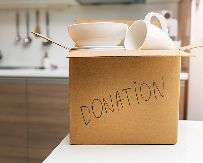A donation box full of dishes in a kitchen.