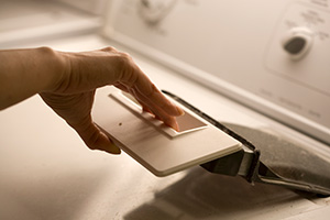Hand pulling out the lint trap from a dryer