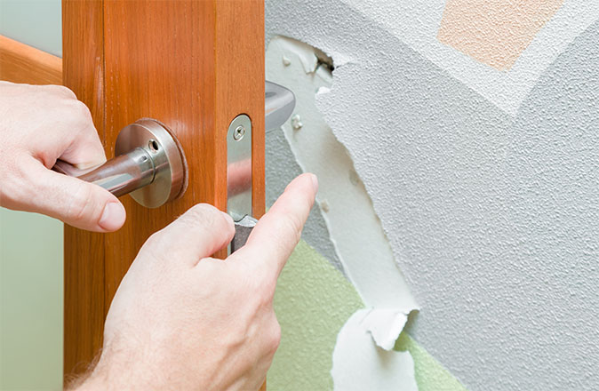 A homeowner points to drywall damage directly behind a door handle.