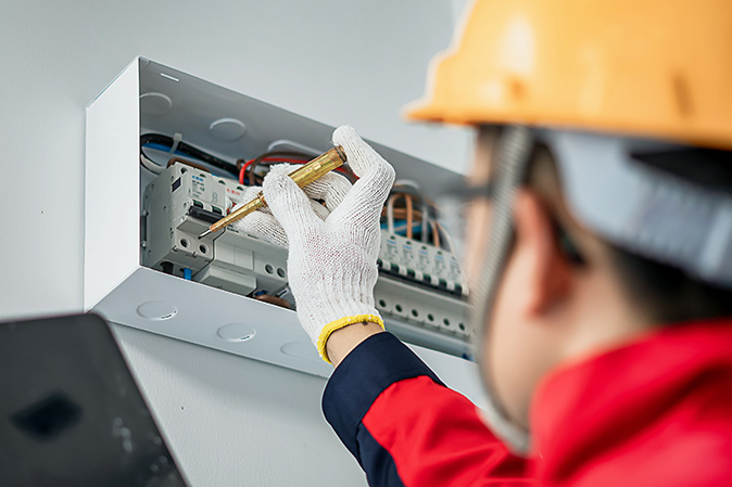 Professional electrician inspecting home electrical panel.