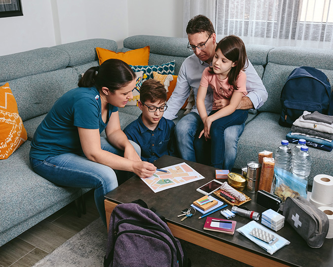 A family sits around their living couch to plan out an emergency plan.