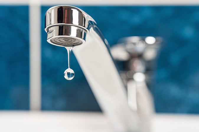 A slow drip falls from a leaky faucet.