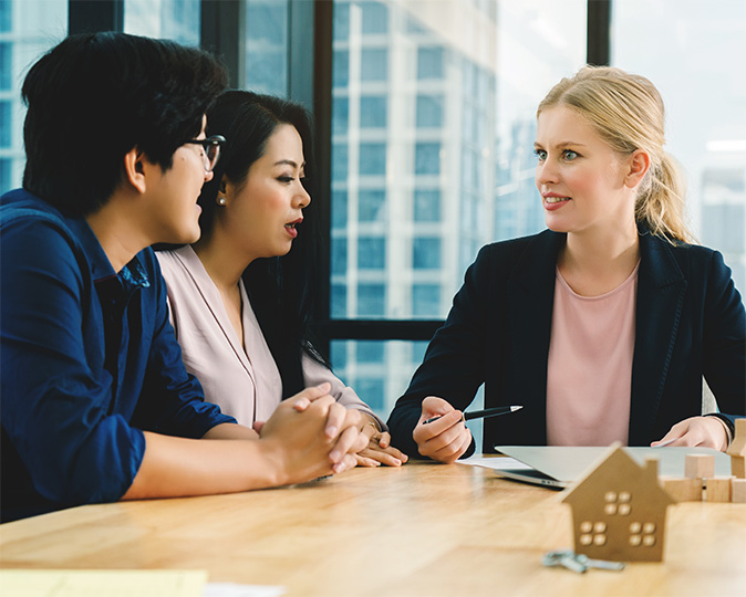 A loan officer sits down to talk with a young couple about their mortgage loan.