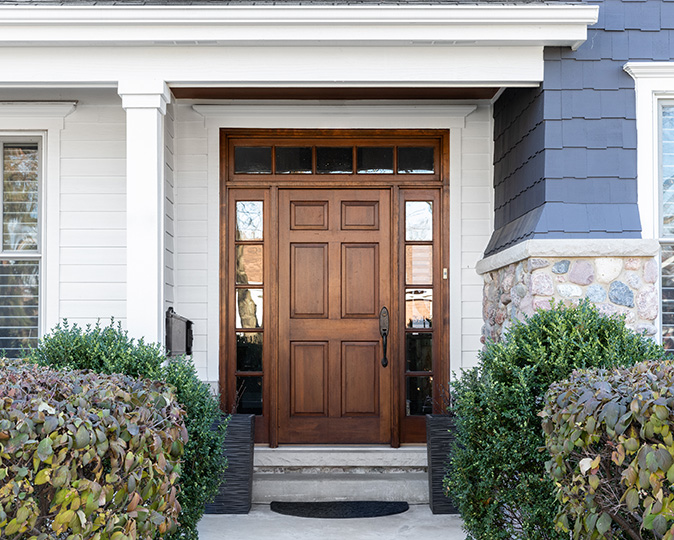 Bright, new solid wood front door surrounded by lush landscaping.