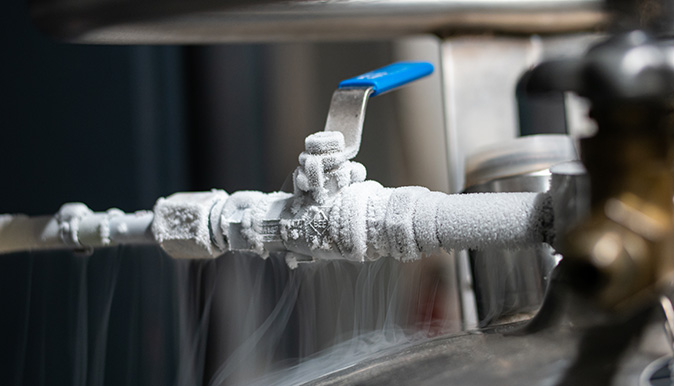 Closeup view of frost coating an exposed pipe in a home's basement.