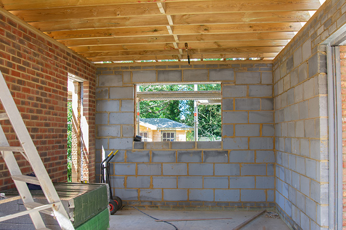 An unfinished renovation project shows walls of exposed building blocks and bricks, and roof structure.