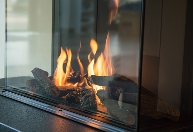 A gas fire burning in a glass fireplace.