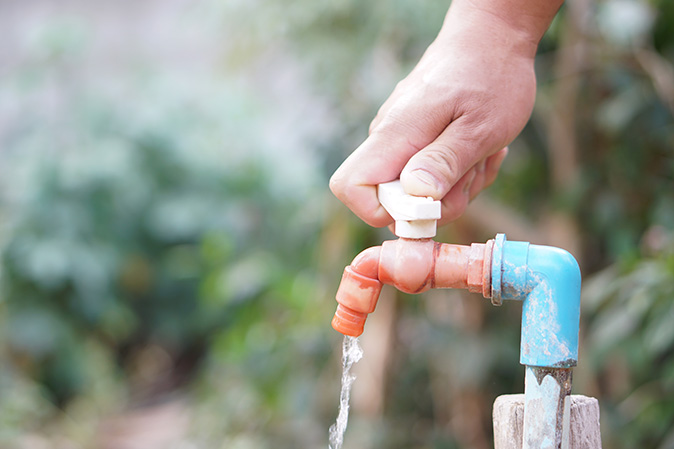 A homeowner is turning off outdoor faucets to complete a task on his fall home maintenance checklist.