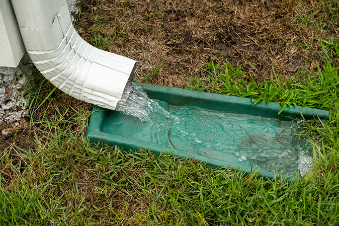 Water gushing from a downspout during heavy rain.