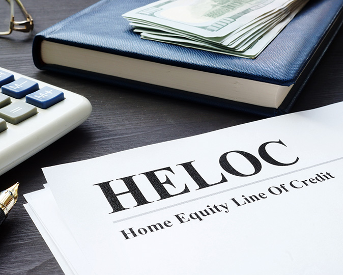 A form labeled “HELOC” sits near a calculator and a stack of bills.