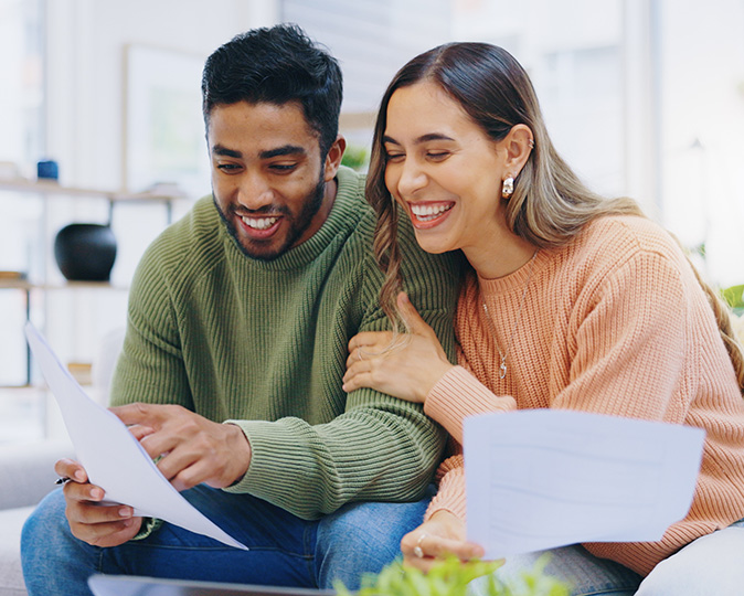 A young couple looks over their finances while sitting on the couch.