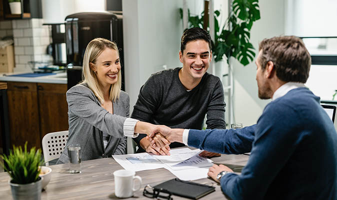 A young couple shakes hands with a lender after securing a HELOC.
