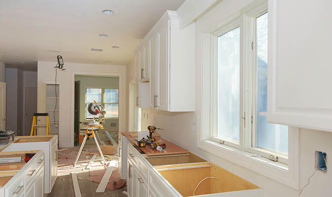 Custom white cabinets and countertops are installed in a spacious kitchen.