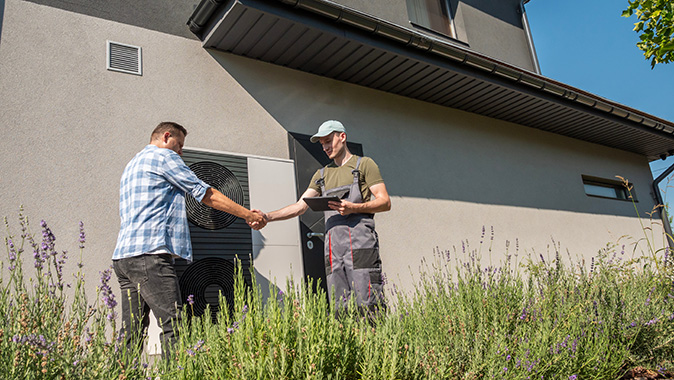 An HVAC technician shakes hands with a homeowner after a system repair.