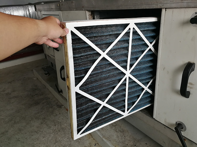 Homeowner checking their HVAC filter to see if it needs replacing.