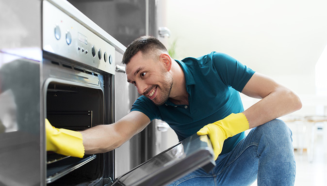 Homeowner cleaning oven in kitchen to get the kitchen ready for fall holidays.