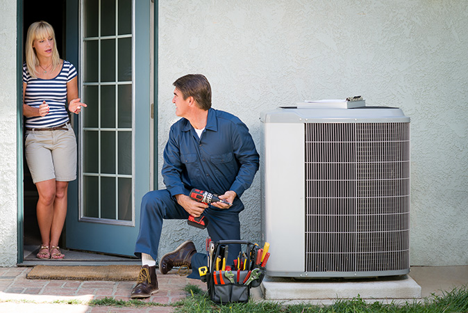 A HVAC maintenance technician talks with his customer during an HVAC inspection.