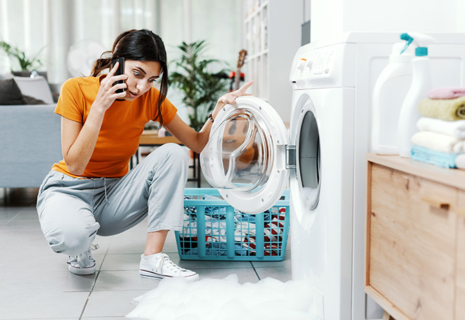 A stunned homeowner is calling an appliance technician about a leaking washer.