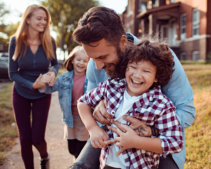 Young homeowners walk happily through a neighborhood with their children.