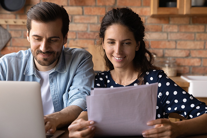 New homeowners review a home warranty coverage contract in a kitchen.