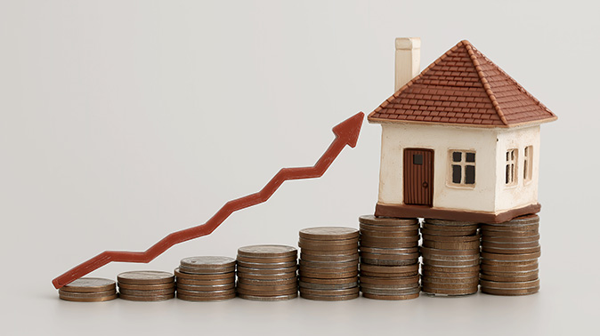 Stacks of coins increase from left to right, with a house atop the tallest stack to represent an upward investment trend.
