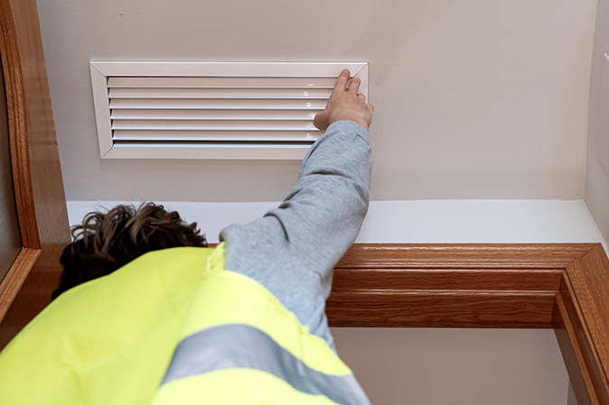 An HVAC technician inspects ductwork as part of a home warranty service call.