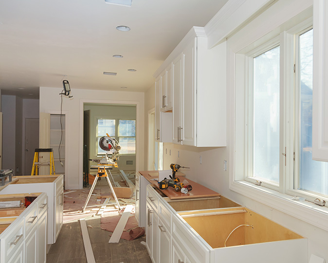 A kitchen under renovation with countertops being replaced and power tools scattered around.