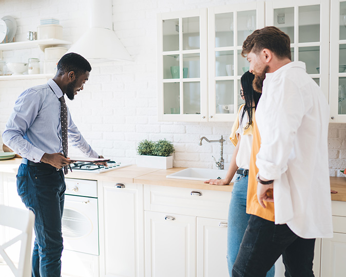 A real estate agent shows a couple around the kitchen of a home 