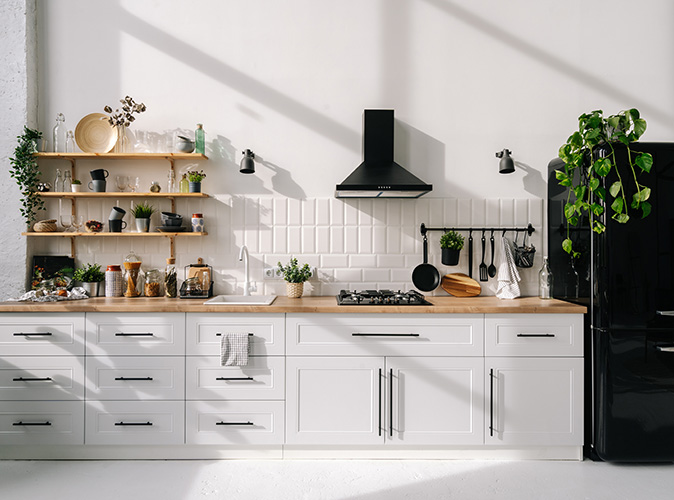 A Scandinavian-style kitchen with minimal design featuring a cooktop, range hood, and refrigerator. 